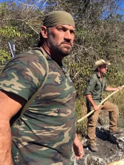 L-R: EJ Snyder und Jeff Zausch halten Speere am Fluss.
