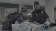 CBP-Beamter Griffin sieht zu, wie CBP-Beamter Hundal mehrere elektronische Geräte untersucht, die in den Sachen eines Kuriers in Dulles, Virginia, gefunden wurden (National Geographic).