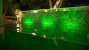 The completed pool lit up at night with an expanded entertainment area and jacuzzi.
