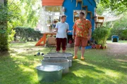Wohltat oder einfach nur eklig? Fritz Fuchs (Guido Hammesfahr, l.) versucht Nachbarn David Paschulke (Daniel Zillmann, r.) für seinen selbstgebauten Barfußpfad zu begeistern.