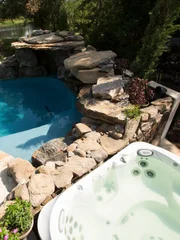 The completed pool in the backyard with a jacuzzi and waterfall.