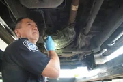 CBP-Beamter Vasquez untersucht mit einer Taschenlampe die Unterseite des Fahrzeugs eines Verdächtigen auf geschmuggelte Drogen in Pharr, Texas. (National Geographic)