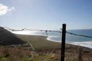 Blick auf die Küste und das Meer durch den Drahtzaun