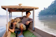A Laotian man steers his wooden boat along the Mekong River near the Pak Ou Caves in Louangphrabang.