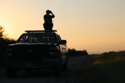 Warden Forrest Price looking through binoculars at sunset.