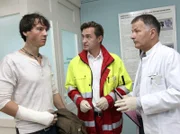 Gero Quitte (Ralph Kretschmar, links) erkundigt sich bei dem Notarzt (Markus Neumann, Mitte) und Dr. Roland Heilmann (Thomas Rühmann) nach dem Zustand der eingelieferten Patientin Marlene Defland.