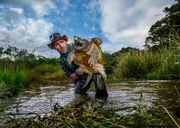 Coyote Peterson in the water holding up a snapping turtle.