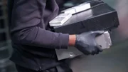 Ein Räuber mit Handschuhen trägt eine Aktentasche und Geld.