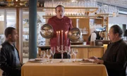 Beissl (Andreas Giebel, r.) und Jerry (Peter Marton, l.) werden im Restaurant Nouvelle Cuisine von Michelle Perrin (Miguel Abrantes Ostrowski, M.) persönlich bedient.