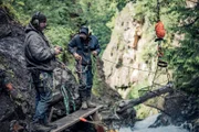 Dustin Hurt and Wes Richardson operate the basket to remove rocks from the creek