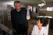Kommissar Stadler (Dieter Fischer, l.) bittet Rechtsmedizinerin Dr. Dimos (Anastasia Papadopoulou, r.), seine Einkäufe kurzzeitig im Kühlschrank zu lagern.