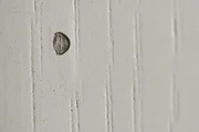Normaler Fensterlack nach Hagelschaden. Feuchtigkeit konnte nach der Beschädigung zum Holz vordringen. Der Lack ist abgesplittert. Die Schutzschicht ist beschädigt.