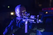 Ein Mann hält ein Scharfschützengewehr.