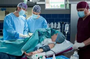 Dr. Ahlbeck (Philipp Danne, l.) und Florian Osterwald (Lion Wasczyk, 2.v.l.) führen einen Eingriff bei Anouk Heise (Clara Apel, 2.v.r. mit Komparse) durch.