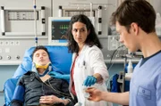 Max Krohn (Oliver Konietzny, l.) hatte einen schweren Autounfall. Dr. Sherbaz (Sanam Afrashteh, M.) und Florian Osterwald (Lion Wasczyk, r.) nehmen den Patienten auf.