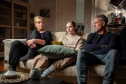 Ina Zimmermann (Melanie Marschke, l.), Lotte Trautzschke (Carlotta Bähre, M.) und Jan Maybach (Marco Girnth, r.) sitzen gemeinsam in Inas Wohnung auf der Couch und machen sich einen gemütlichen Abend.