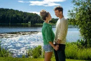 Lea (Vita Tepel) und Mik (Florian Frowein) stehen sich am grünen Ufer eines schillernden Gewässers gegenüber, und sehen sich verliebt in die Augen.