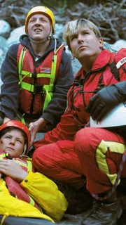 Sanitäter Peter Berger (Serge Falck), der schwer verletzte Hannes (Wolfgang Seybert) und sein Freund Alex (Manuel Löffler) beobachten gespannt, wie Dr. Lüdwitz am Seil vom Medicopter zur Unfallstelle abgeseilt wird.
