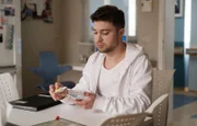 Kris Haas (Jascha Rust) versucht eine abgebrochene Ecke des Handys seiner Kollegin Miriam zu reparieren.