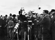 Premierminister Neville Chamberlain winkt der Menge am Heston Airport
