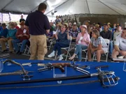 A table full of antique weapons behind him, Sean Rich speaks to one of the patrons at the auction.