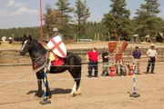 A medieval enthusiast on horseback brings an extra horse for the joust.