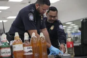 Die CBP-Beamten De La Cruz und Nikirk testen mit einem Gemini-Gerät am internationalen Flughafen von Philadelphia den Inhalt eines selbstgemachten Weins, der im Gepäck eines Reisenden gefunden wurde.