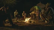 Hazen sitzt mit Einheimischen im Dorf am Lagerfeuer.