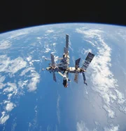 Die russische Raumstation Mir wird auf Film festgehalten, während sie während des letzten Rundflugs der Shuttle-Mir über dem blau-weißen Planeten Erde schwebt.