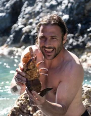 Hazen Audel hält einen Hummer, den er mit der Hand im Meer gefangen hat.