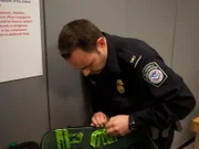CBP Officer Sal Sinatra tapes up the broken suitcase.