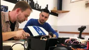 Norman (l.) is working on a Ford Mustang Shelby GT 350 while Johannes Perly watches him.