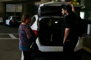 LORI picking up her son, ANDREW, from the airport.