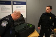 Jamaica, New York, USA: CBP officers Chris Elias (left) and Sal Sinatra look into a suitcase that has heroin in the lining. (Photo Credit: National Geographic Television)