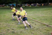 The tug of war team lean far back to try and put as much force into the pull as possible.