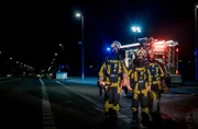 Drei Feuerwehrmänner der Feuerwehr Bochum nachts auf dem Weg zum Einsatz.