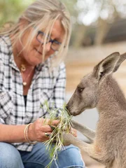 Theresa sitting down feeding a kangaroo.