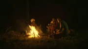 Hazen Audel sitzt mit zwei Einheimischen vom Stamm der Okiek am Lagerfeuer.