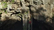 Hazen Audel klettert über Baumwurzeln zum Eingang der Höhle.