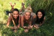 Tawny, Phaedra, and Alyssa laying with their weapons in the grass.