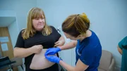 Medium Shot of Dr Emma examining Raelene's Lipoma on her stomach