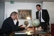 Generalmajor Rudolf Stirner (Joseph Lorenz, l.) bekommt von Oberst Ernst Kanter (Hary Prinz, r.) eine Liste mit den Namen der Opfer. Kanter misstraut Stirner. Will er ihn auf die Probe stellen?