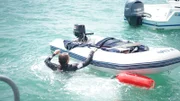 Diver in water swimming up to dinghy