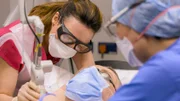 Mid shot of Dr Emma, masked up, using laser on Tony H's chest