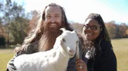 Joe Watts and Myesha Price smiling while holding a goat in Centre, AL.