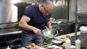 Host Robert Irvine shows them a recipe for sliders, as seen on Food Network's Restaurant: Impossible, Season 13.