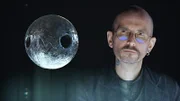 Der Kriminalbiologe Mark Benecke untersucht eine stecknadelkopfgroße, durchlöcherte Metallkugel, die im Körper eines toten Mannes gefunden wurde.