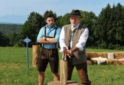 ARD STURM DER LIEBE FOLGE 1847, Für den Wettbewerb "Das Gesicht Bayerns" erteilt Alfons (Sepp Schauer, r.) Goran (Saša Kekez, l.) eine Lektion im Holzhacken.