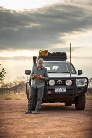 Portrait shot of Jeremy leaning against 4x4 car reading his notebook Location: Western Australia