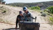 Ryan (drone operator) and crew look at the drone resting on top of a pelican case.